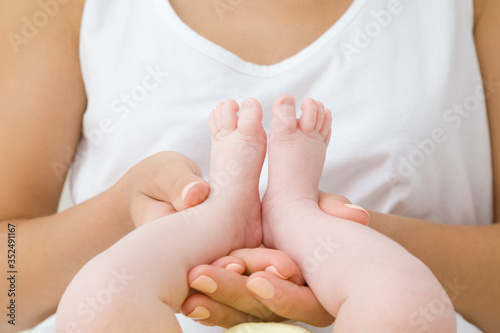 Young mother hands holding her infant little feet. Playing with baby. Lovely, emotional moment. Relationship concept. Closeup.