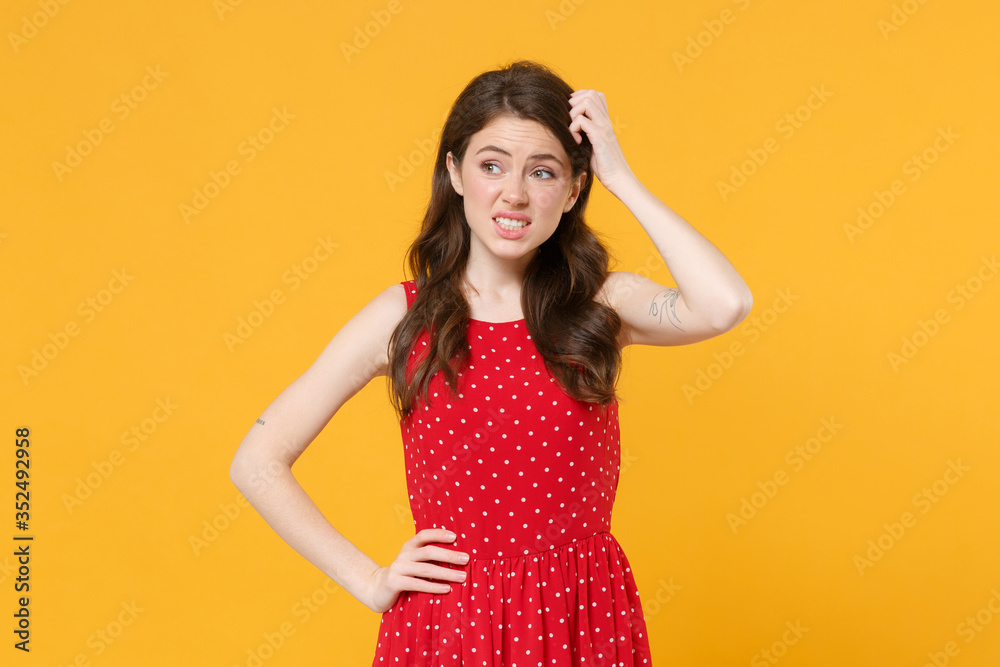 Preoccupied young brunette woman girl in red summer dress posing isolated on yellow wall background studio portrait. People sincere emotions lifestyle concept. Mock up copy space. Put hand on head. Preoccupied young brunette woman girl in red summer dress posing isolated on yellow wall background studio portrait. People sincere emotions lifestyle concept. Mock up copy space. Put hand on head.