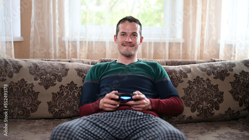 A man sits on the couch and plays the prefix at home