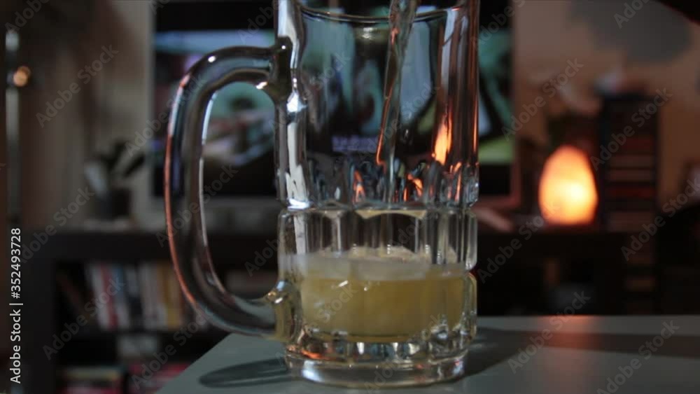 close-up, a man pours beer from the bottle into the glass while watching tv close-up, a man pours beer from the bottle into the glass while watching tv