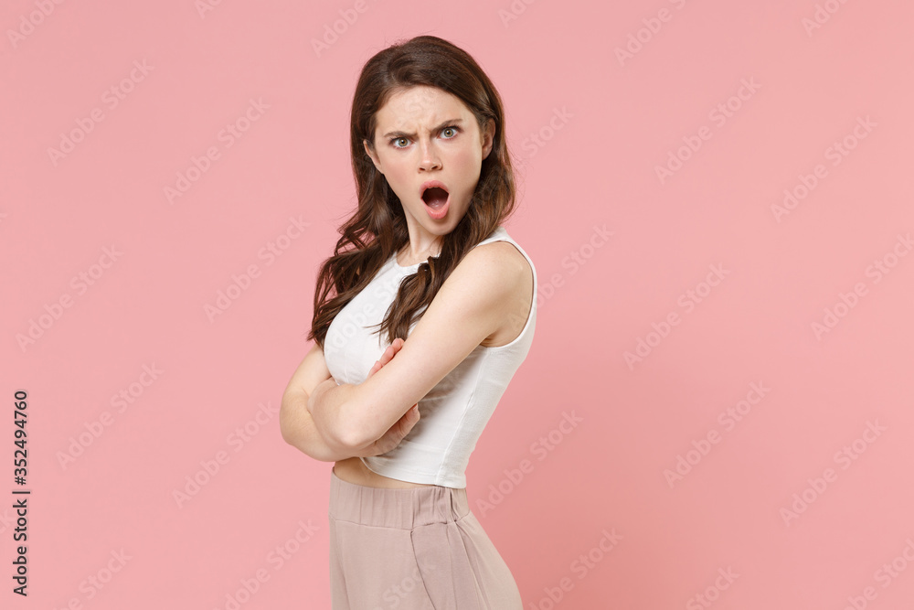 Side view of shocked young brunette woman girl in light casual clothes posing isolated on pastel pink background. People lifestyle concept. Mock up copy space. Holding hands crossed looking camera. Side view of shocked young brunette woman girl in light casual clothes posing isolated on pastel pink background. People lifestyle concept. Mock up copy space. Holding hands crossed looking camera.