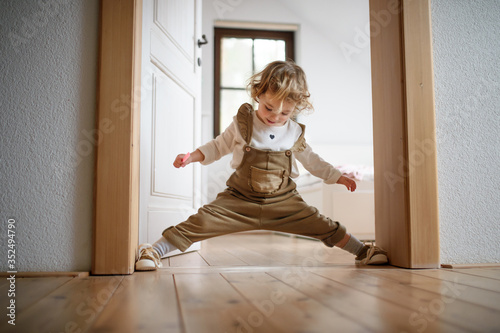 Fotografie Small toddler girl standing indoors at home, having fun.