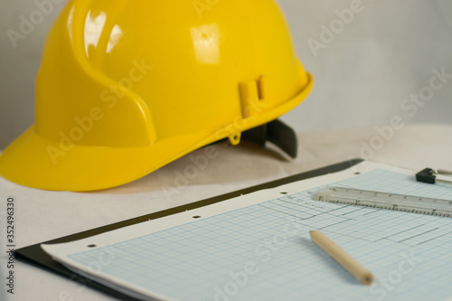 Pencil and drawings on graph paper with ruler and yellow hard safety hat