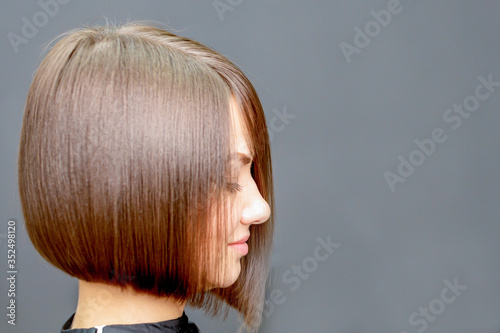 side view of face portrait of young woman with short hairstyle in the hairdress studio.