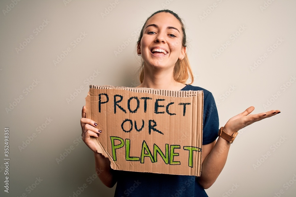 Young beautiful blonde woman with blue eyes asking for protect planet holding banner very happy and excited, winner expression celebrating victory screaming with big smile and raised hands Young beautiful blonde woman with blue eyes asking for protect planet holding banner very happy and excited, winner expression celebrating victory screaming with big smile and raised hands