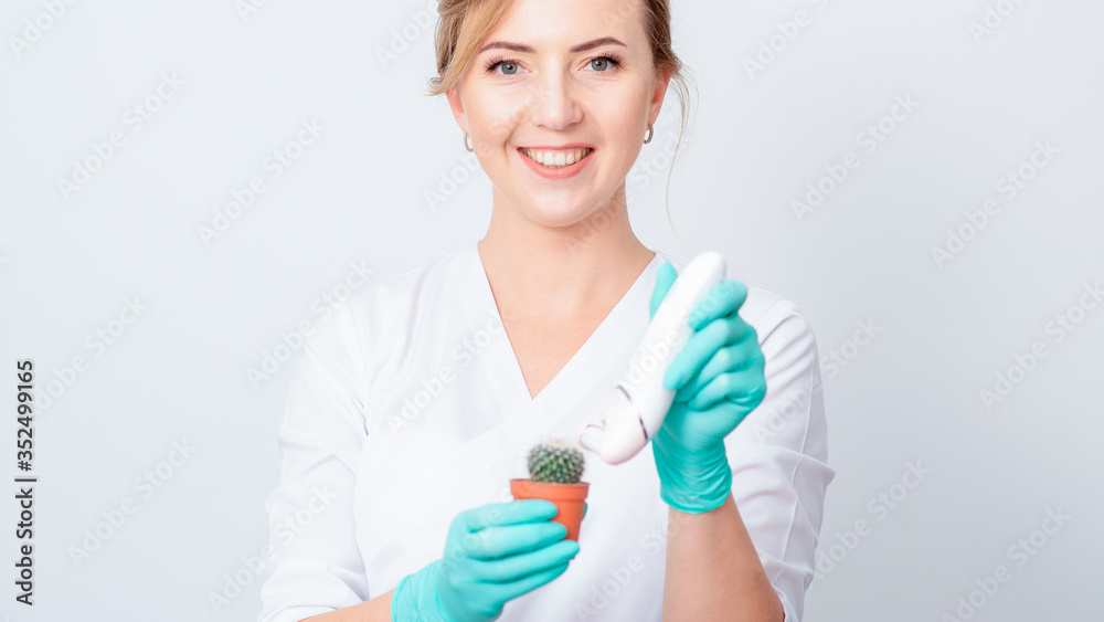 Portrait of smiling cosmetologist shaving green cactus in a brown pot by electric epilator on white background. Portrait of smiling cosmetologist shaving green cactus in a brown pot by electric epilator on white background.