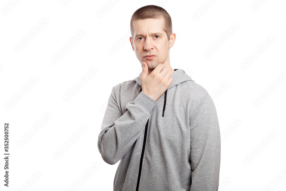 brooding, insecure male athlete makes a decision, a hand at the chin. Dressed in a grey hooded jacket. A look into the camera. Isolated brooding, insecure male athlete makes a decision, a hand at the chin. Dressed in a grey hooded jacket. A look into the camera. Isolated