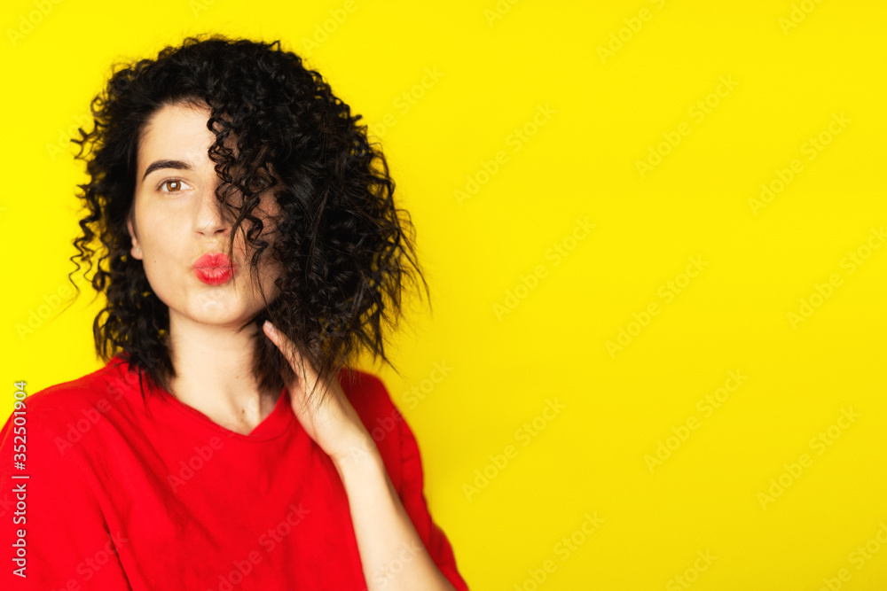 Charming young girl with curly black hair in a red T-shirt on a yellow background. Portrait photography. Emotions, facial expressions. Curls, Brunette. Red lipstick
Charming young girl with curly black hair in a red T-shirt on a yellow background. Portrait photography. Emotions, facial expressions. Curls, Brunette. Red lipstick