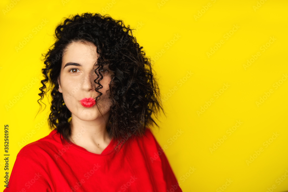 Charming young girl with curly black hair in a red T-shirt on a yellow background. Portrait photography. Emotions, facial expressions. Curls, Brunette. Red lipstick
Charming young girl with curly black hair in a red T-shirt on a yellow background. Portrait photography. Emotions, facial expressions. Curls, Brunette. Red lipstick