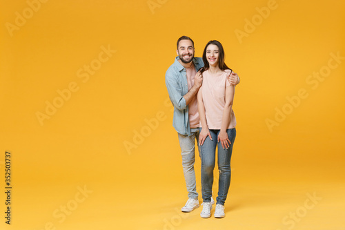 Smiling young couple two friends guy girl in pastel blue casual clothes posing isolated on yellow wall background studio portrait. People lifestyle concept. Mock up copy space. Hugging looking camera.