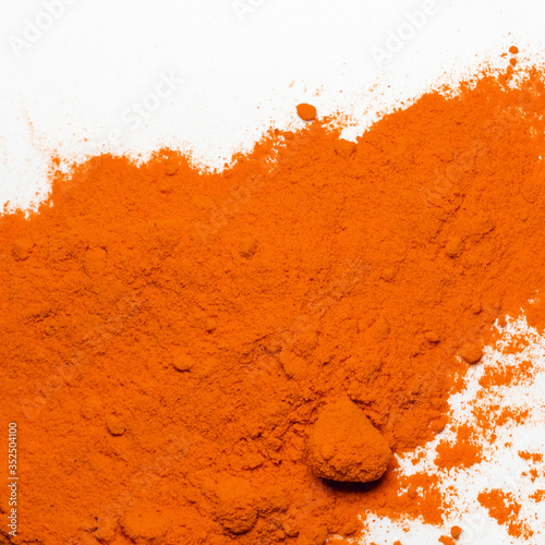 The loose red orange cosmetic or food powder ingredient on white background. Paprika spice. Colorful texture of pigment. Copy space. Close-up. Top view