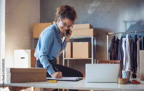 Young businesswoman working at her office. Young small business entrepreneur using smart phone at workplace.