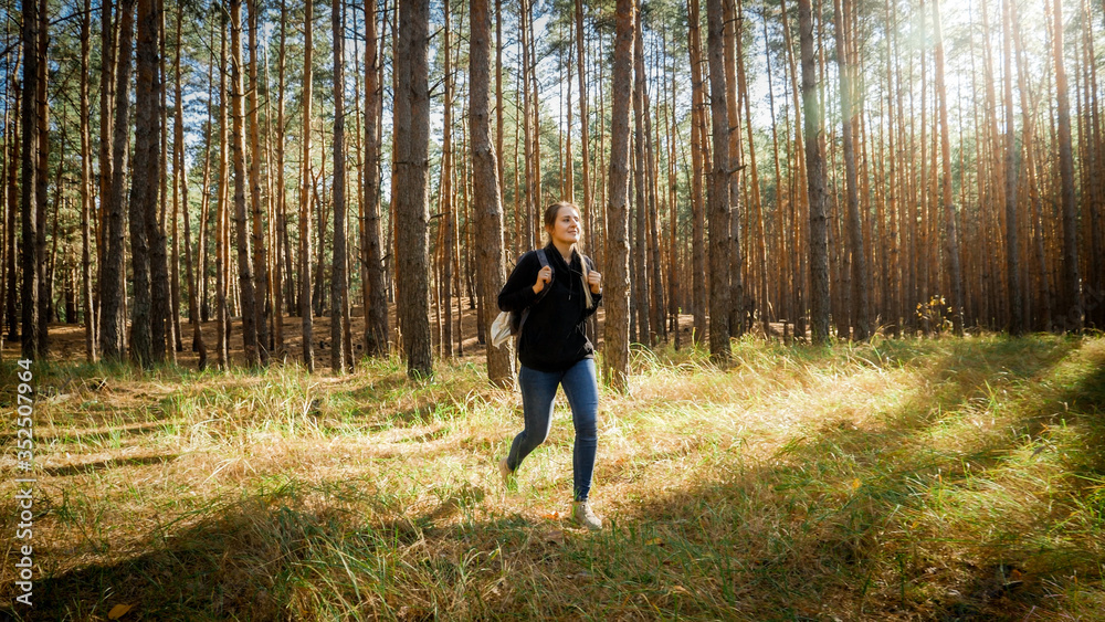 Obraz premium Beautiful female hiker with backpack walking out of the forest on the meadow