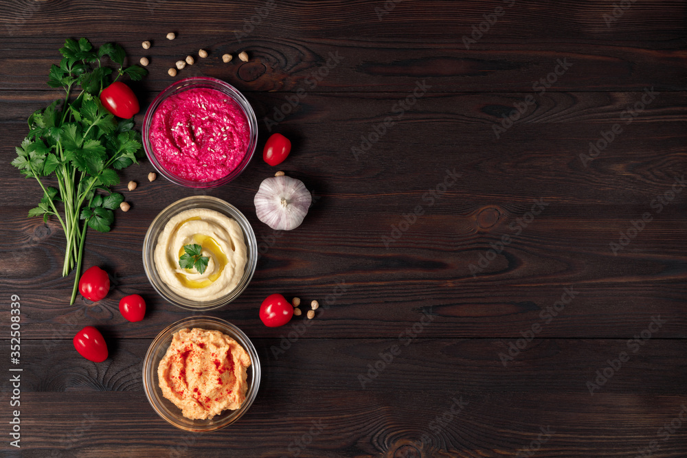Colorful hummus bowls with crispy bread on wooden table Colorful hummus bowls with crispy bread on wooden table