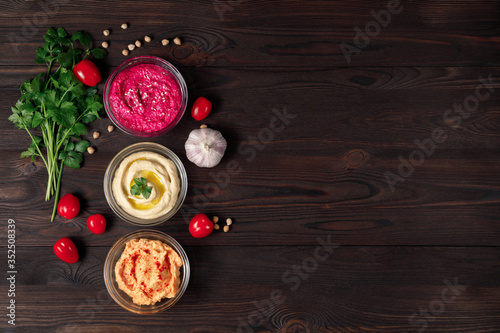 Colorful hummus bowls with crispy bread on wooden table