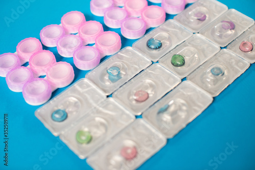 Color contact lenses in blisters and contact lens cases on blue background