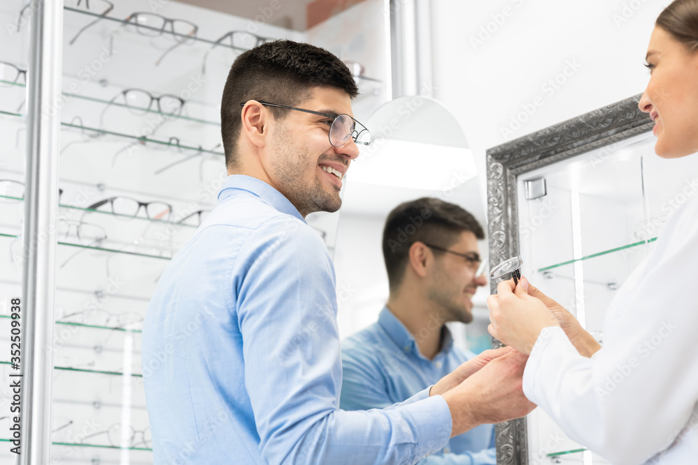 Optometrist helping young guy to choose glasses Optometrist helping young guy to choose glasses