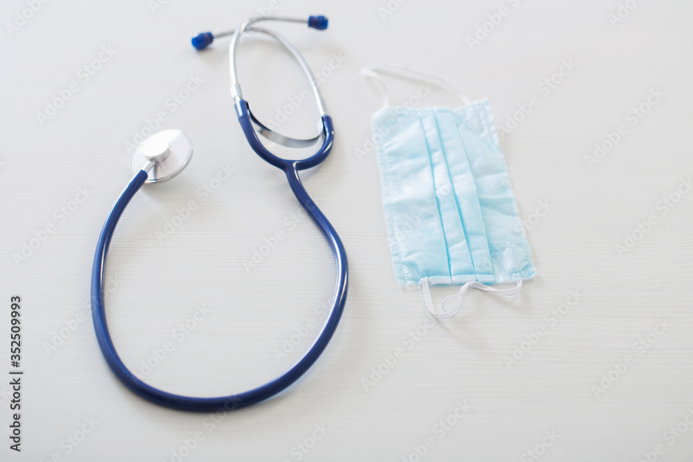 medical mask and stethoscope on white wooden table medical mask and stethoscope on white wooden table