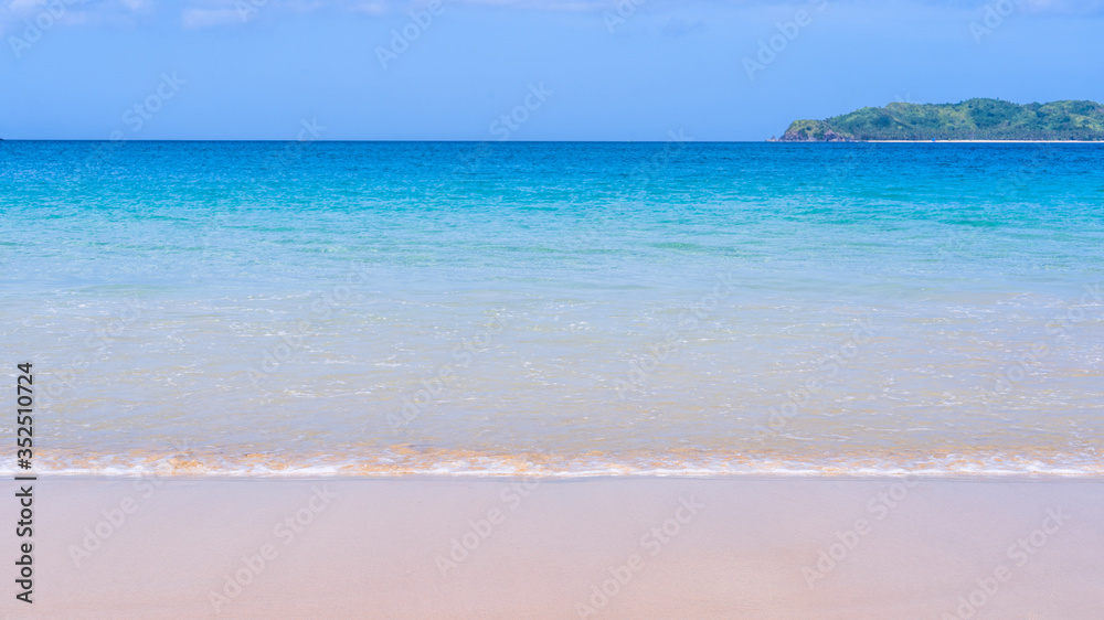 Beautiful amazing gold colored sandy beach with soft waves isolated with sunny blue sky. Concept of tropical calm tourism idea, copy space, close up