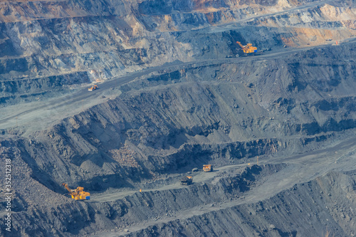 Huge iron ore quarry with working dump trucks and excavators