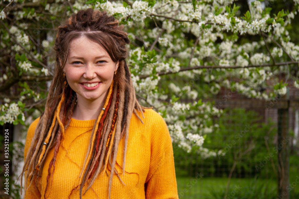 girl with dreadlocks smiles on a background of blooming cherry girl with dreadlocks smiles on a background of blooming cherry