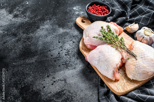 Raw chicken thigh, organic poultry meat. Black background. Top view. Copy space