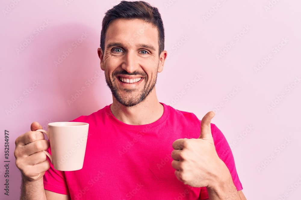 Young handsome man drinking cup off coffee standing over isolated pink background smiling happy and positive, thumb up doing excellent and approval sign Young handsome man drinking cup off coffee standing over isolated pink background smiling happy and positive, thumb up doing excellent and approval sign