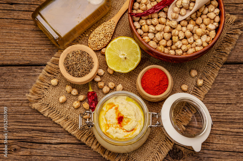 Hummus on old wooden boards background. Dry chickpea, olive oil, lemon, cumin and chili pepper