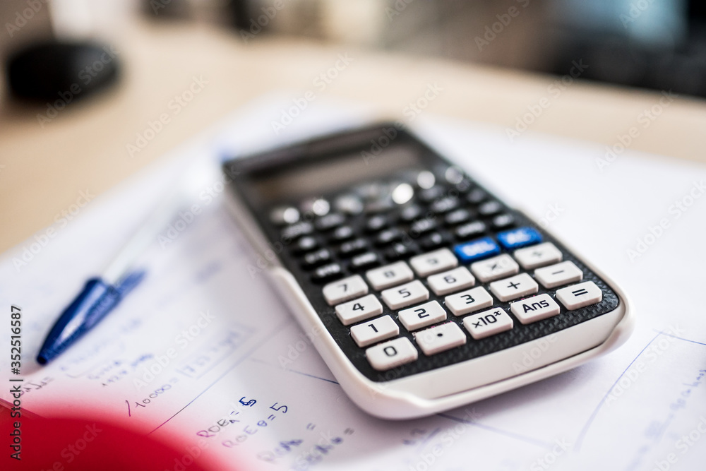 Close up: portable calculator and pen on a sheet of paper with mathematical formulas. Bokeh background. Close up: portable calculator and pen on a sheet of paper with mathematical formulas. Bokeh background.