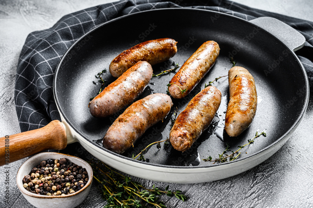 Tasty homemade sausages in a pan. Pork, beef and chicken meat.  Gray background. Top view