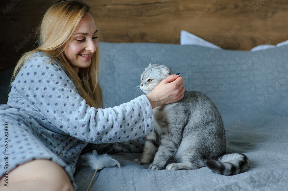 Beautiful young woman with cute cat on a bed Beautiful young woman with cute cat on a bed