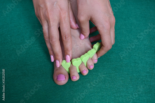 Foot of a woman having a pedicure and putting on a pink nail polish