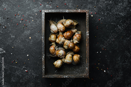 Grape snails with parsley in a wooden box. Top view.