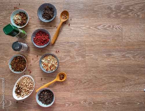 Spices, seasonings, chickpeas in plates and banks on a wooden table. Space for text. Background with spices and seasonings.