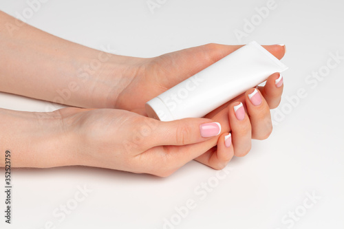 Female hand holding cosmetic bottle on white