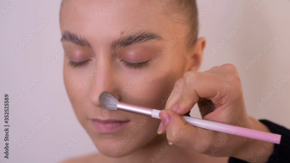 Beautiful young girl does herself professional makeup in a beauty salon by a makeup artist. Models apply foundation on the skin and corrective makeup. The work is done with makeup brushes. soft focus Beautiful young girl does herself professional makeup in a beauty salon by a makeup artist. Models apply foundation on the skin and corrective makeup. The work is done with makeup brushes. soft focus