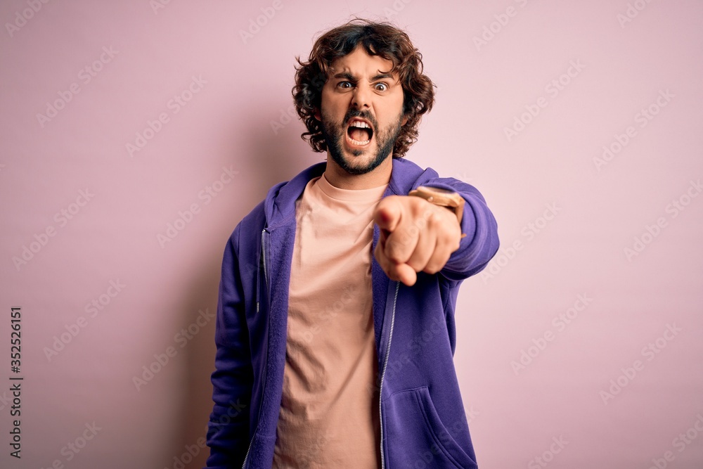 Young handsome sporty man with beard wearing casual sweatshirt over pink background pointing displeased and frustrated to the camera, angry and furious with you Young handsome sporty man with beard wearing casual sweatshirt over pink background pointing displeased and frustrated to the camera, angry and furious with you