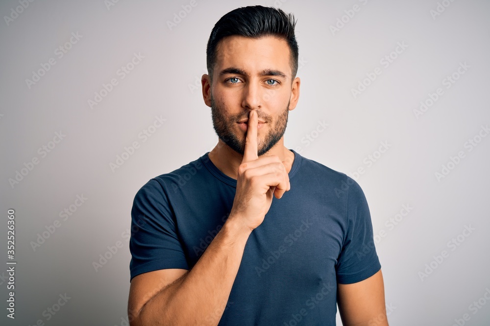 Young handsome man wearing casual t-shirt standing over isolated white background asking to be quiet with finger on lips. Silence and secret concept. Young handsome man wearing casual t-shirt standing over isolated white background asking to be quiet with finger on lips. Silence and secret concept.