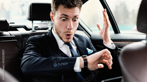 Stressed young businessman looking at wrist watch in car © Prostock-studio