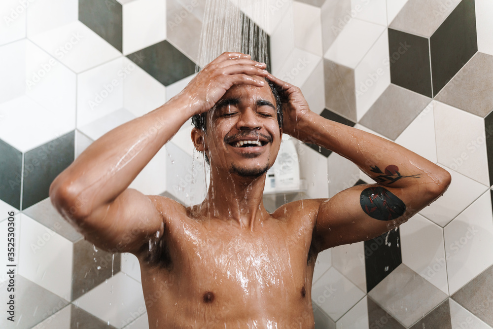 Photo of half-naked african american man smiling while taking shower Photo of half-naked african american man smiling while taking shower