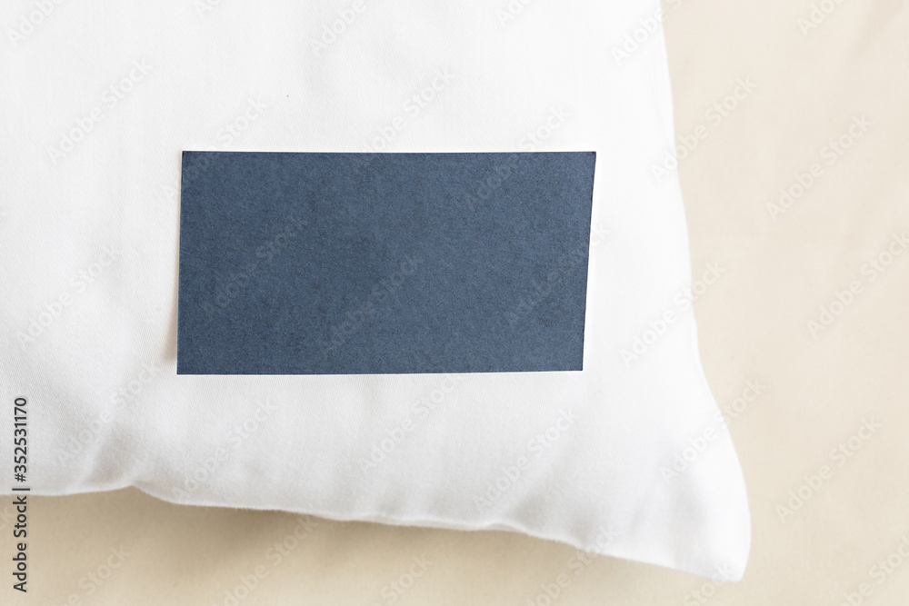Fototapeta premium Blank paper business card on a hotel pillow
