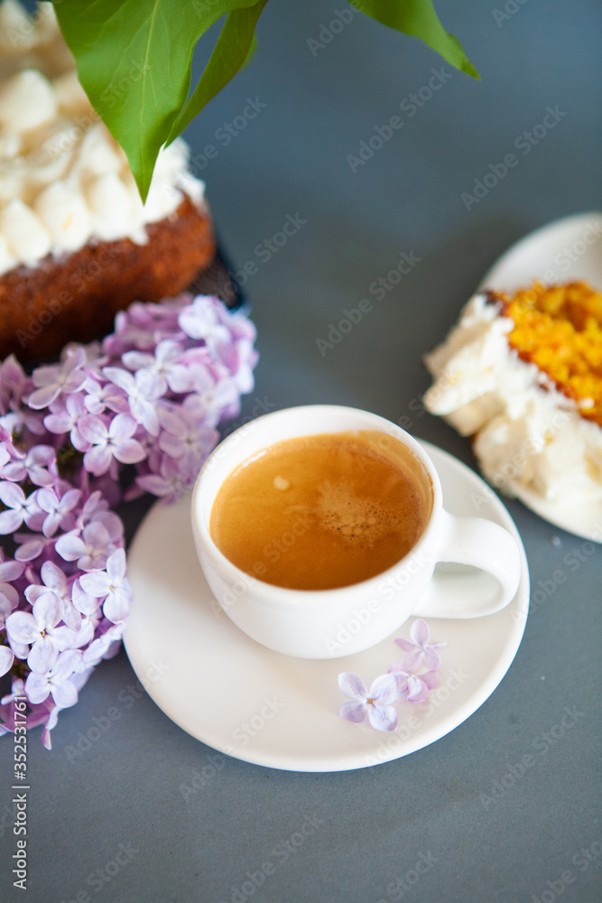 Fresh espresso in a white cup and lilac flowers on the background. Fresh espresso in a white cup and lilac flowers on the background.
