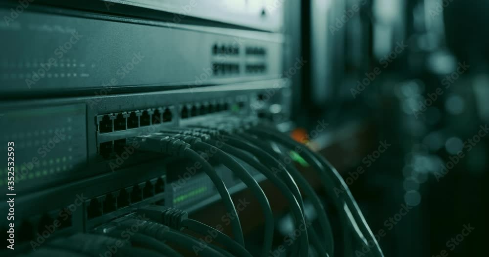 Networking hardware with attached RJ45 ethernet cables working in a dark datacenter room