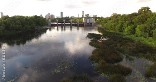 4K cloudy afternoon aerial scenic footage of Mnevniki hydro system dam regulating Moscow River water levels overlooking green park, distant city sky scrapers in Krylatskoye area in Moscow, Russia