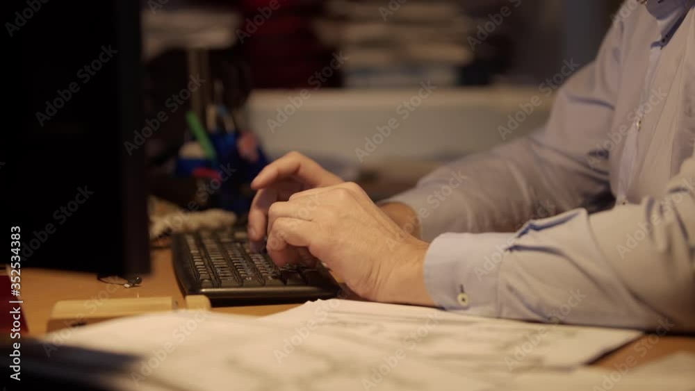 Late at Night in the Office. Design Engineer Works on His Personal Computer. Businessman Working Alone. Graphic Designer Overworked On Computer Late Night. Man typing on keyboard Late at Night in the Office. Design Engineer Works on His Personal Computer. Businessman Working Alone. Graphic Designer Overworked On Computer Late Night. Man typing on keyboard