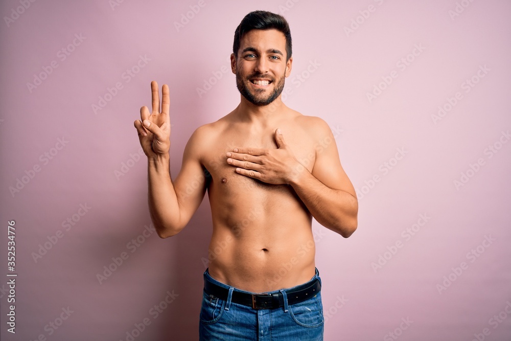 Young handsome strong man with beard shirtless standing over isolated pink background smiling swearing with hand on chest and fingers up, making a loyalty promise oath