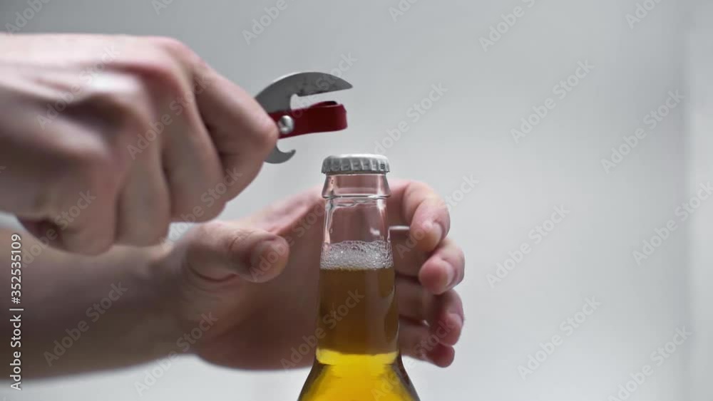 cropped view of man opening bottle of beer with can opener on grey background cropped view of man opening bottle of beer with can opener on grey background