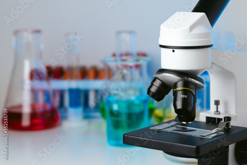 Scientific laboratory with microscope and test tubes with samples, close up photo