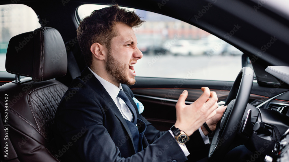 Angry young businessman driving alone in his new car