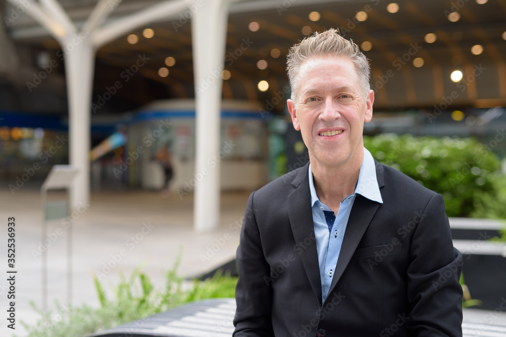 Happy mature businessman smiling in the city outdoors